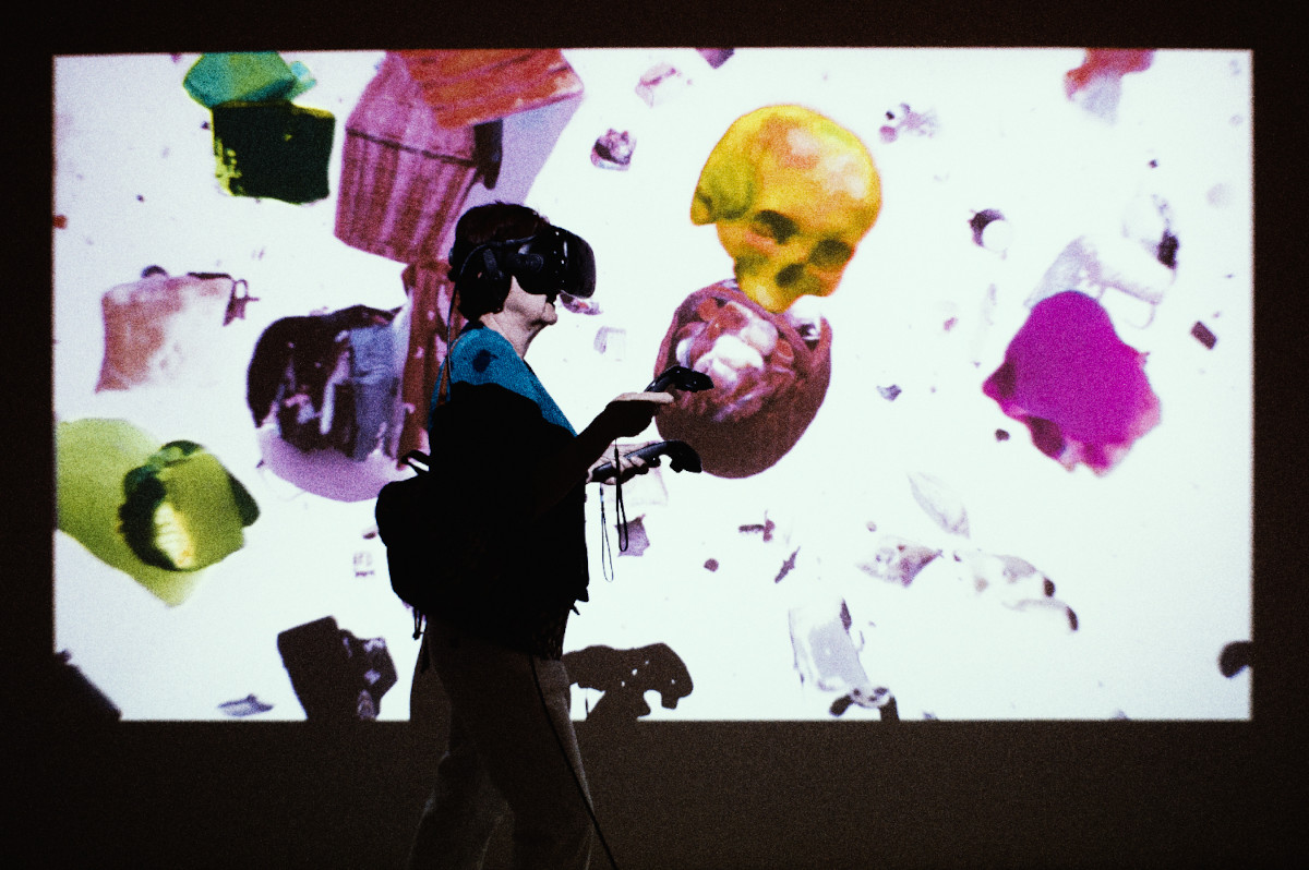 woman with VR headset and controllers in front of a projected video