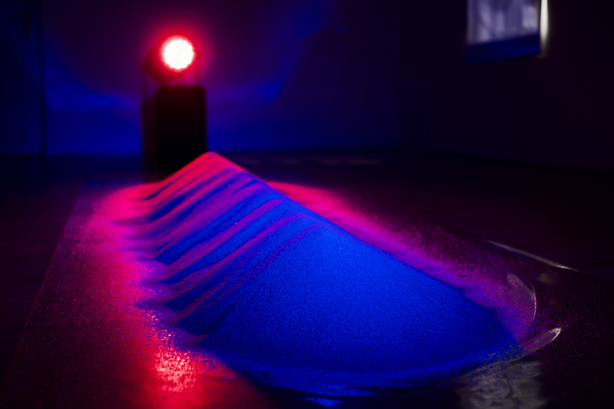 lamp artistically illuminates sand with blue and pink colors