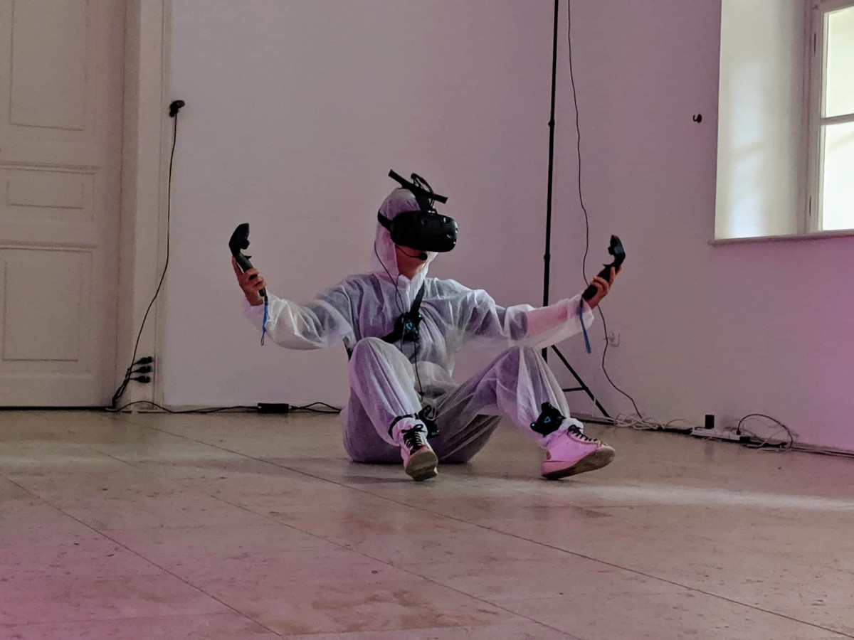Artist performing in VR accessories sitting on the ground
