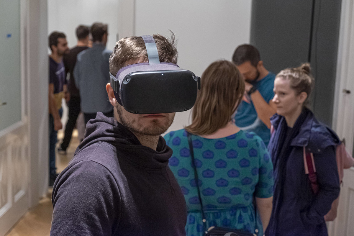 Man wearing a virtual reality headset and visitors of the Design Week