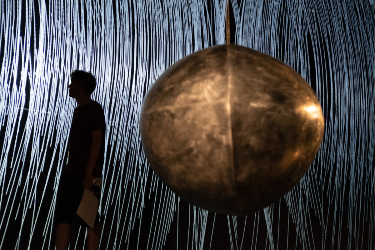 pendulum sculpcutre and a visitor of the exhibition