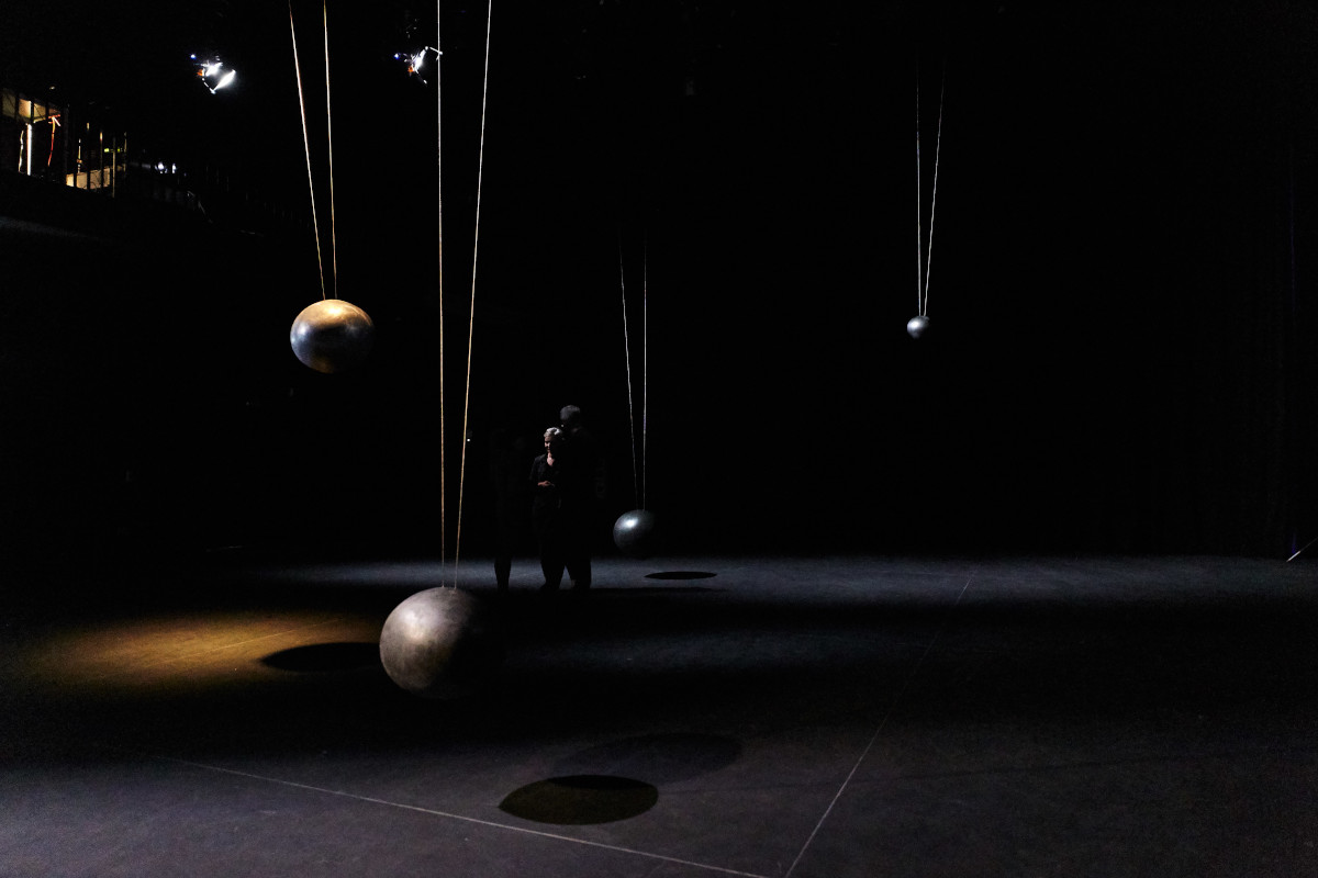 woman watching moving pendulums in the exhibition space