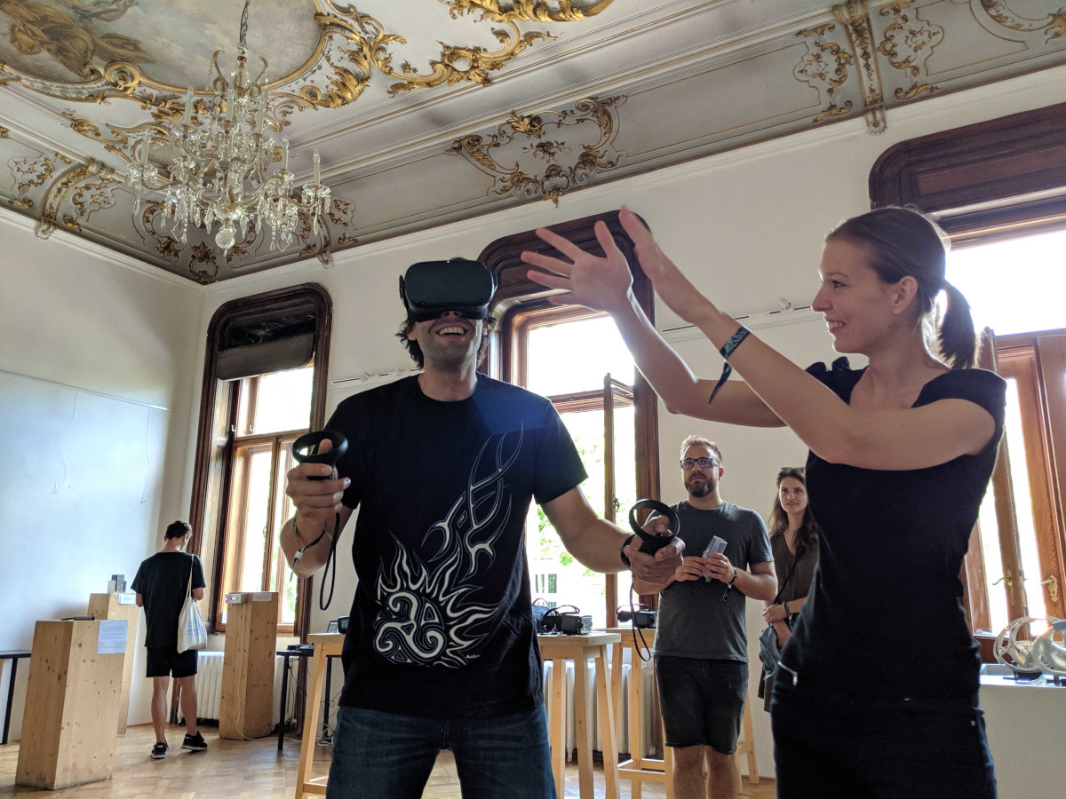 woman explaining VR experience to a man wearing virtual reality headset and holding controllers